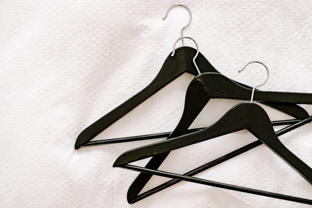 Black hangers lying on an organized bed.